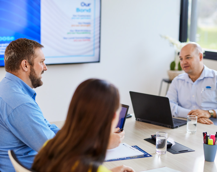 Three BlueScope employees seated and talking in a board room